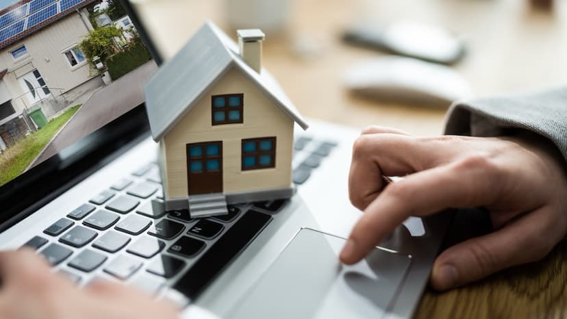 Property analysis on laptop with house model representing real estate technology